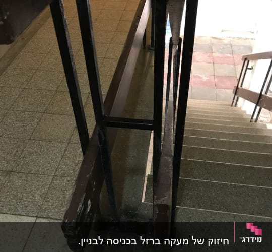 מעקה מתכת שחור עם מסגרת עץ חום במדרגות